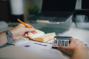 A self-employed worker reviews receipts, invoices, and tax documents beside a laptop.